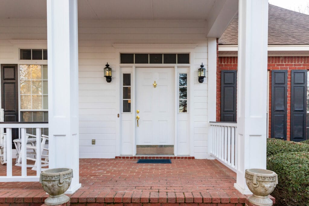 Classic white entry door with brass fixtures flanked by sidelights and elegant black shutters, installed by Keystone Window, welcoming visitors to a Pennsylvania home.