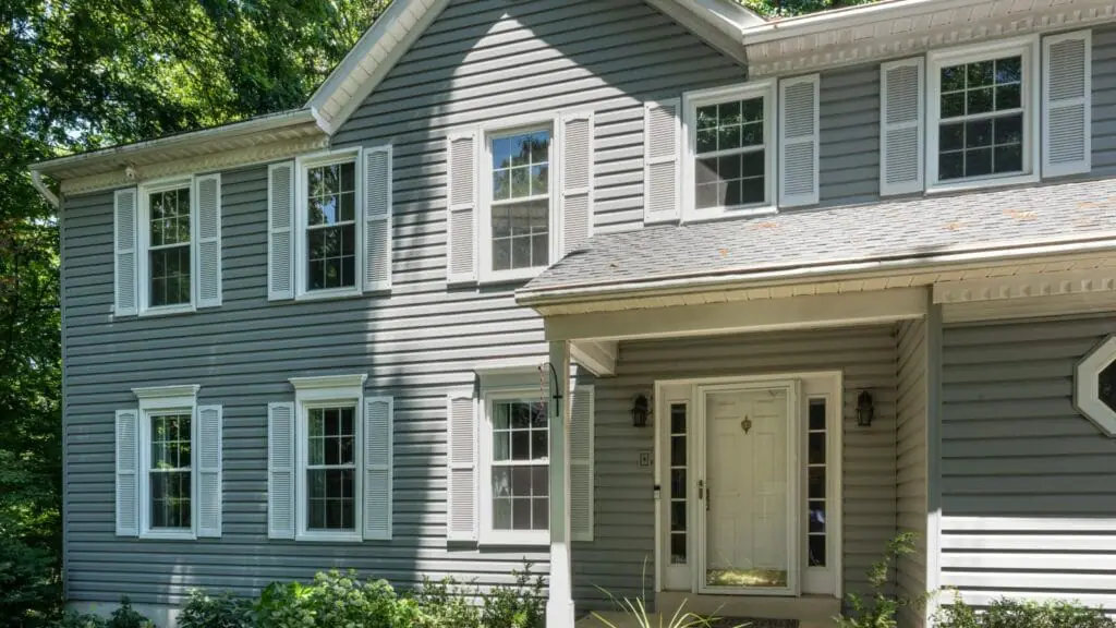 Traditional two-story home with gray siding featuring multiple white Keystone replacement windows, enhancing its classic architecture and curb appeal